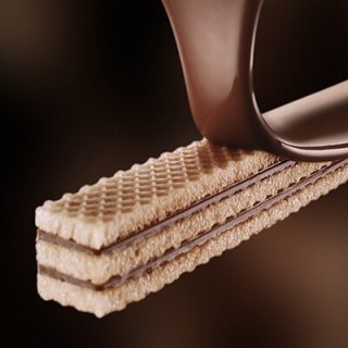 A crisp wafer finger being covered in milk chocolate